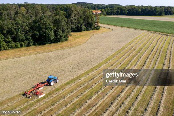 traktor mit ausrüstung auf dem feld - heu stock-fotos und bilder