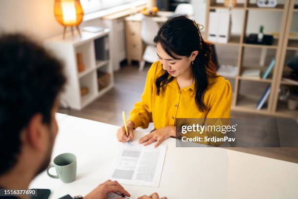 donna giapponese che firma il contratto, durante un incontro con un agente immobiliare maschio - contratto foto e immagini stock