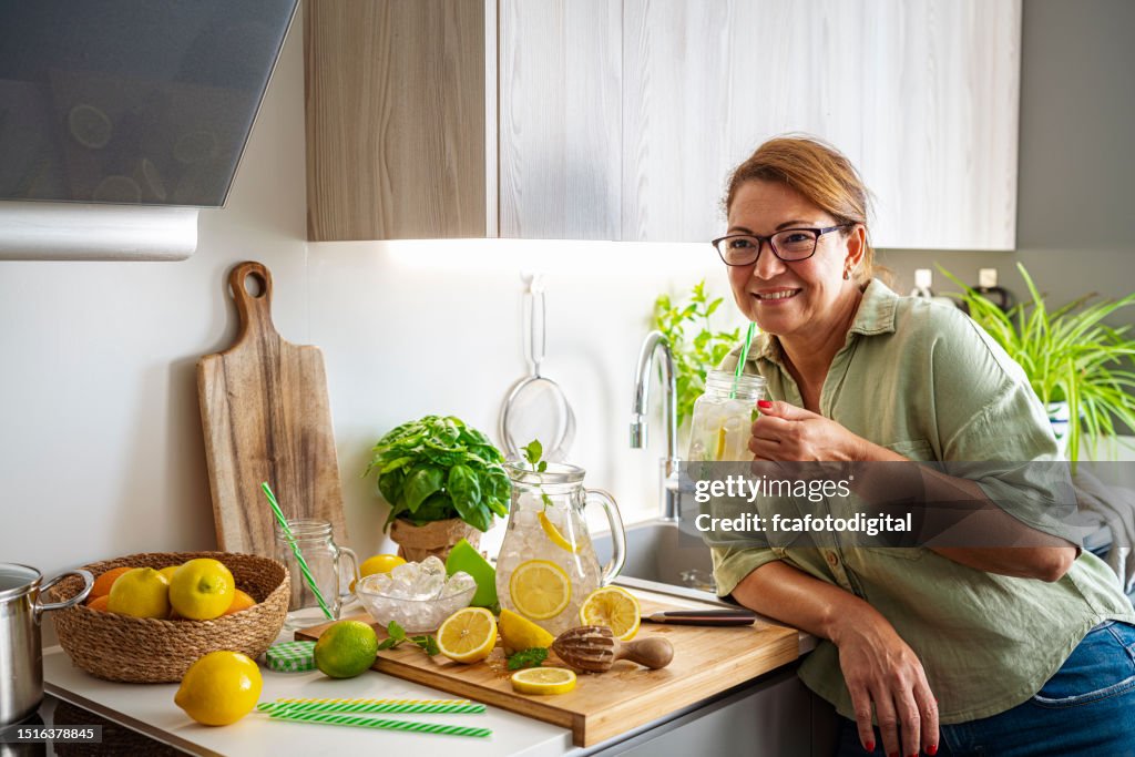 Woman enjoying fresh lemonade in kitchen