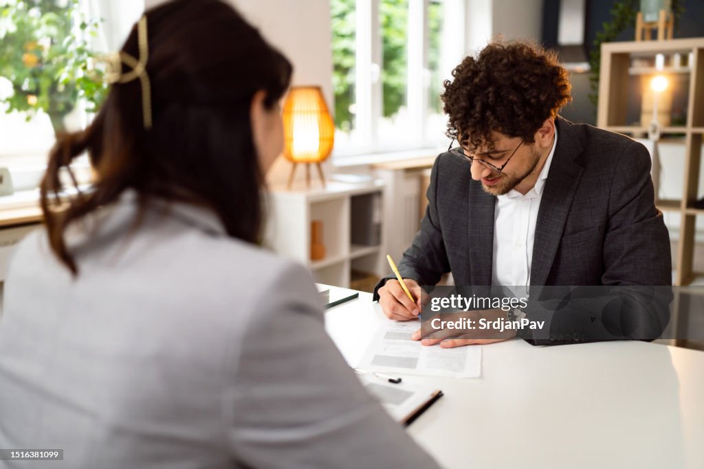 Male candidate signing the contract, during a meeting with a female recruiter Japanese ethnicity