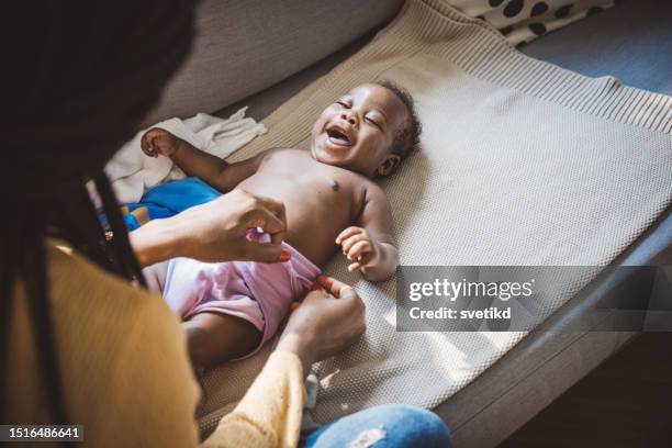 liebevolle mutter, die sich um ihr baby kümmert - mum changing nappy stock-fotos und bilder