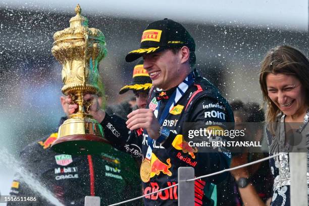 Winner Red Bull Racing's Dutch driver Max Verstappen holding the trophy reacts as second placed McLaren's British driver Lando Norris sprays...