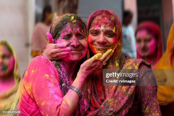 mature indian women celebrating holi festival, india - holi portraits stock pictures, royalty-free photos & images