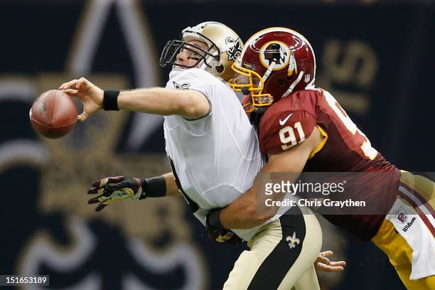 Drew Brees of the New Orleans Saints throws the ball as he is tackled by Ryan Kerrigan of the Washington Redskins during the season opener at...