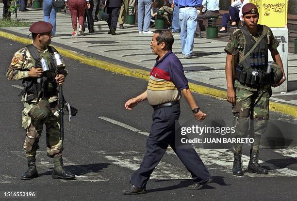 Man crosses the street while Venezuelan National Guards patrol near the Presidential Palace in Caracas 04 December, 2002. Venezuela's opposition...