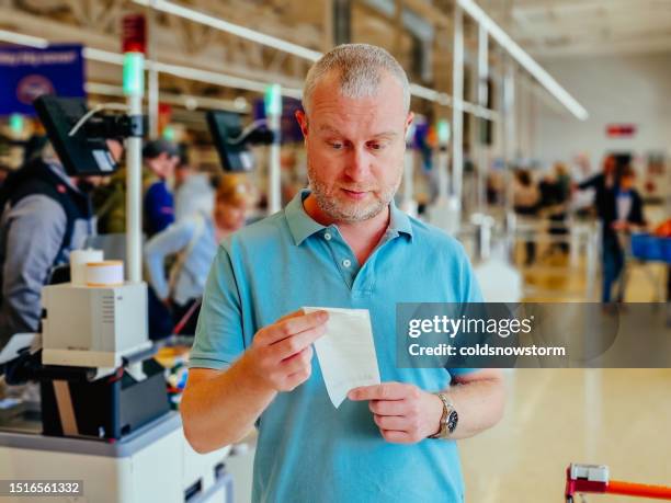 worried man checking the bill in the supermarket - grocery receipt stock pictures, royalty-free photos & images