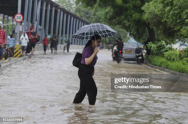 Commuters cross a waterlogged strech following heavy monsoon rains at sector-38 near Tau Devi Lal Stadium, on July 9, 2023 in Gurugram, India....