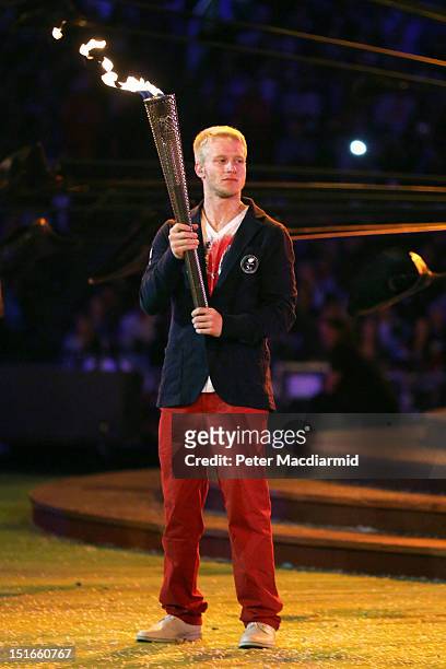 Athlete Jonnie Peacock lights a torch from the flame of the Paralympic cauldron as it is extinguished during the closing ceremony on day 11 of the...