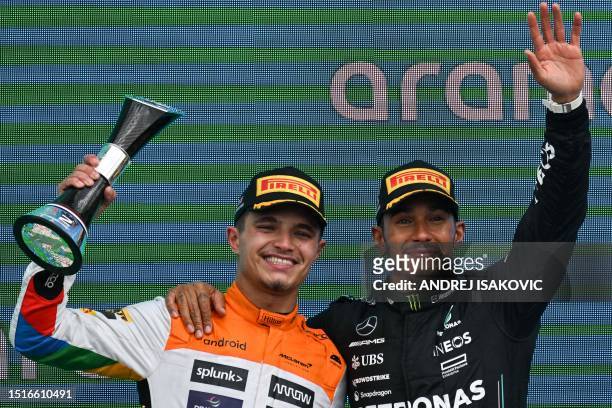 Second placed McLaren's British driver Lando Norris and third placed Mercedes' British driver Lewis Hamilton celebrate on the podium for the Formula...