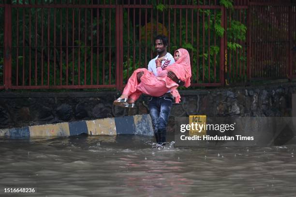 Commuters seen moving through water logged street after heavy rains at Bhairav Marg on July 9, 2023 in New Delhi, India. Delhi-NCR was drenched with...
