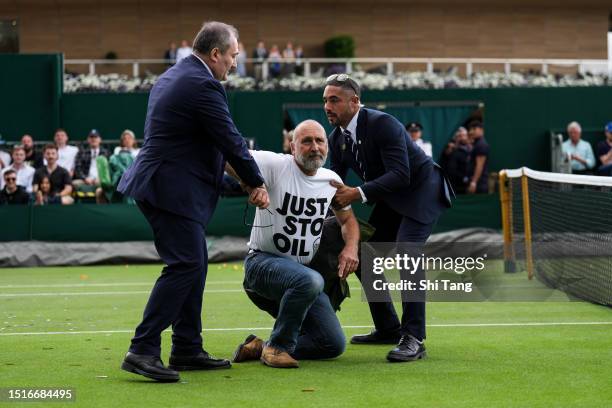 Securities attempt to clear the court after protesters interrupted the Men's Singles first round match between Sho Shimabukuro of Japan and Grigor...
