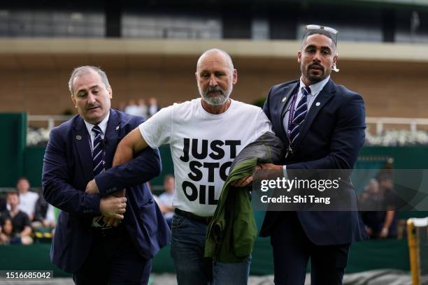 Securities attempt to clear the court after protesters interrupted the Men's Singles first round match between Sho Shimabukuro of Japan and Grigor...