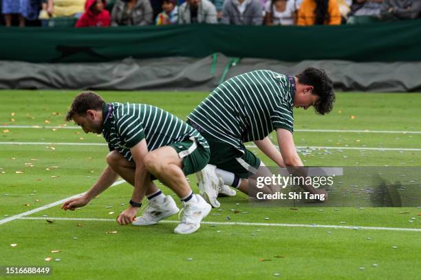 Two members of the ground staff clear the court after protesters interrupted the Men's Singles first round match between Sho Shimabukuro of Japan and...