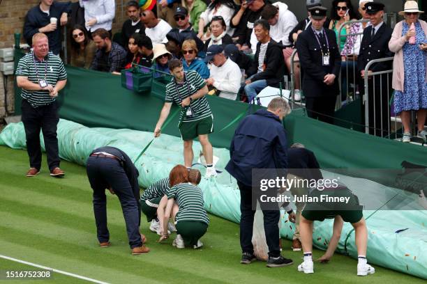 Ground staff clear confetti and a jigsaw puzzle from the Court 18 Men's Singles first round match between Sho Shimabukuro of Japan and Grigor...