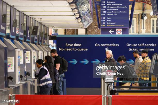 Passengers purchase rail tickets from self-service machines in Victoria Station on July 05, 2023 in London, England. The Rail Delivery Group backed...