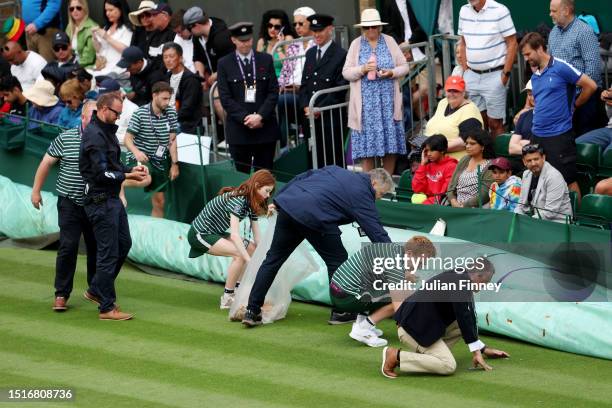 Ground staff clear confetti and a jigsaw puzzle from the Court 18 Men's Singles first round match between Sho Shimabukuro of Japan and Grigor...