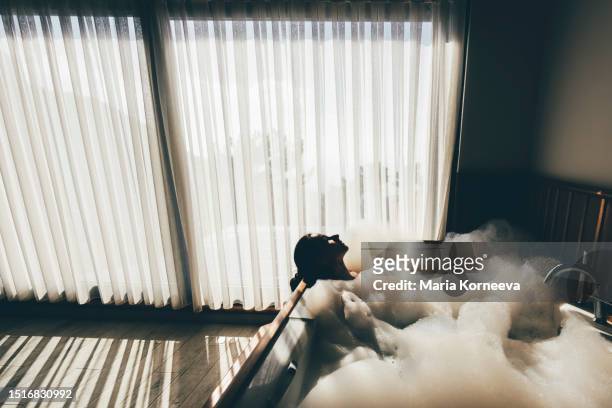 woman relaxing in hot tub in a hotel room. - bubblebath stock pictures, royalty-free photos & images