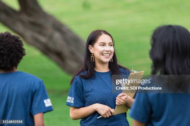 el sonriente coordinador de eventos para adultos jóvenes lleva el portapapeles - organizador de eventos fotografías e imágenes de stock