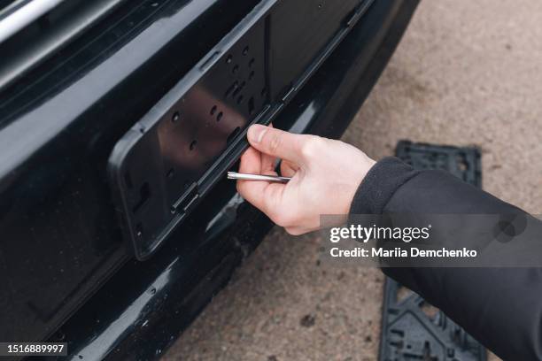 man unscrews license frame of car - license plate stockfoto's en -beelden