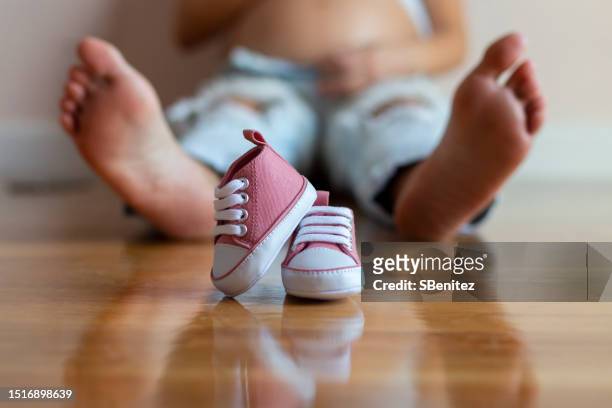 baby shoes in the foreground, in the background his future mom - 赤ちゃんの靴 ストックフォトと画像