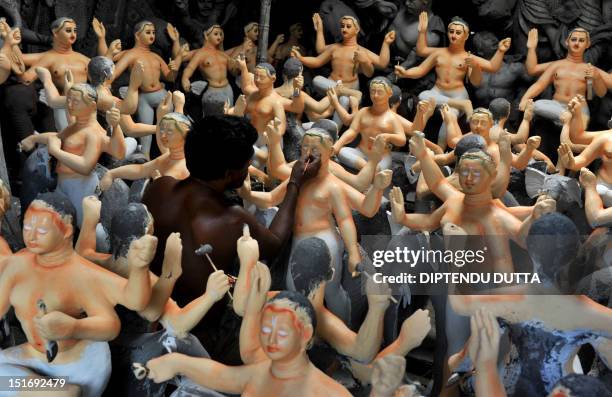 An Indian artist works on an idol of the Hindu god Biswakarma at the artisan village, known locally as Kumartoli, in Siliguri on September 10,2012....