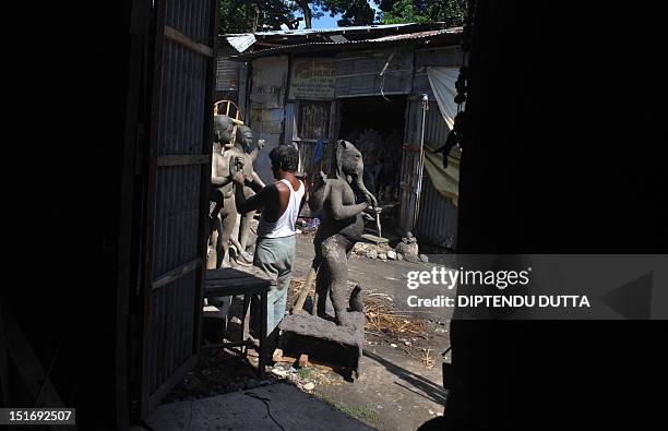 An Indian artist works an idol of the Hindu god Biswakarma at the artisan village, known locally as Kumartoli, in Siliguri on September 10,2012....