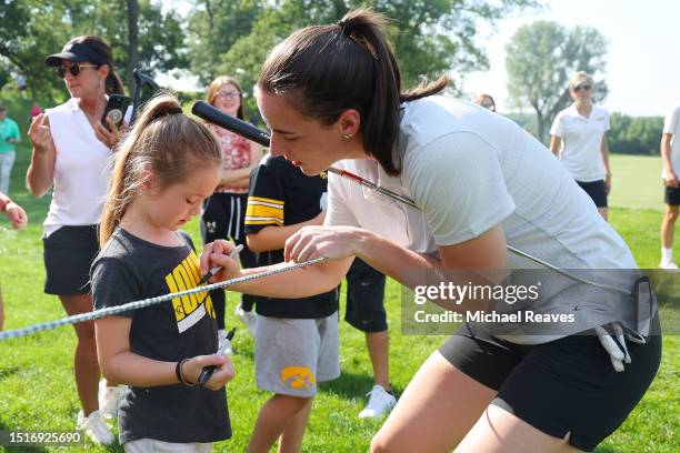 Caitlin Clark of the Iowa Hawkeyes signs a autograph for a young fan during the pro-am prior to the John Deere Classic at TPC Deere Run on July 05,...