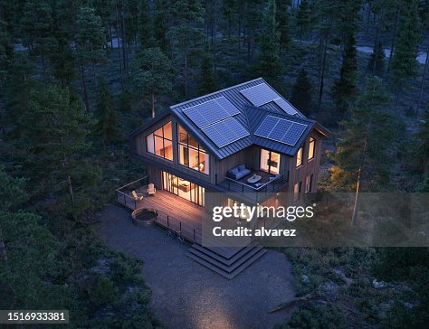 3d render of modern forest house with solar panels on roof at night 3d render of modern forest house with solar panels on roof at night