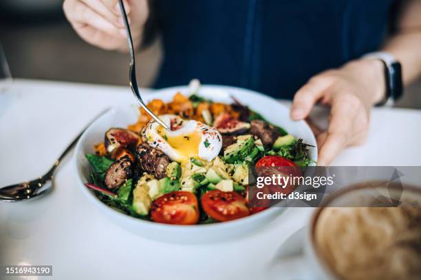 close up shot of a woman eating a dish of fresh beef cobb salad with a soft boiled egg and coffee at a cafe table. enjoying her healthy and nutritious lunch. maintaining a healthy and well-balanced diet. the concept of healthy eating lifestyle - dieta cetogénica imagens e fotografias de stock