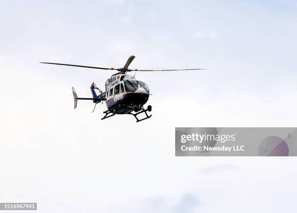 Fire Island Pines, N.Y.: On shark patrol, a police helicopter moves across the sky above beachgoers of Fire Island Pines, New York on July 4, 2023.