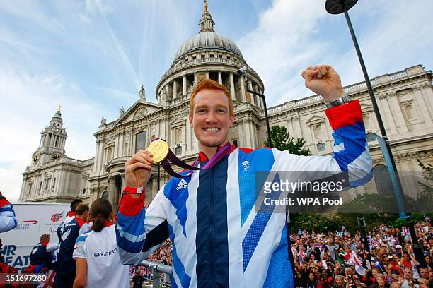 British Olympic gold medal winning athlete Greg Rutherford holds his long jump gold medal as he takes part in the parade passing St Paul's Cathedral...