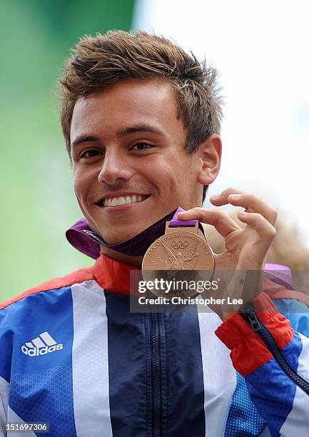 Swimmer Tom Daley shows his medal to the crowd during the London 2012 Victory Parade for Team GB and Paralympic GB athletes on September 10, 2012 in...