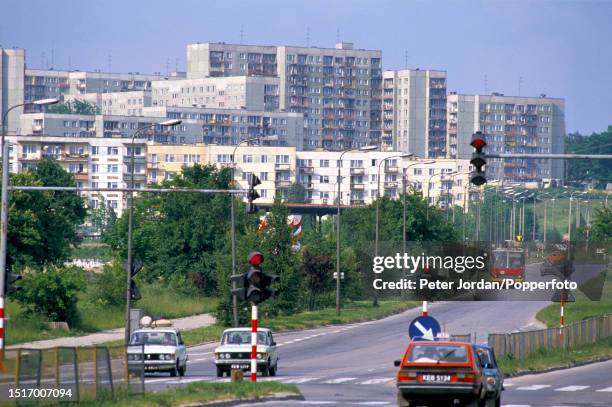 Cars and a bus drive past apartments and blocks of flats comprising a housing estate in a suburb of the city of Katowice in Silesia Province of...