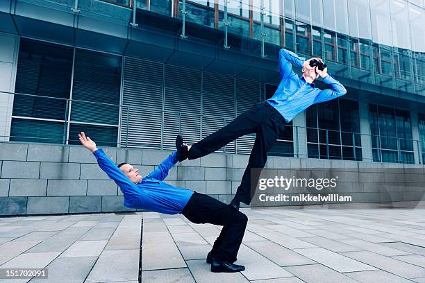 two businessmen performing an acrobatic stunt together - surveillance society stock pictures, royalty-free photos & images