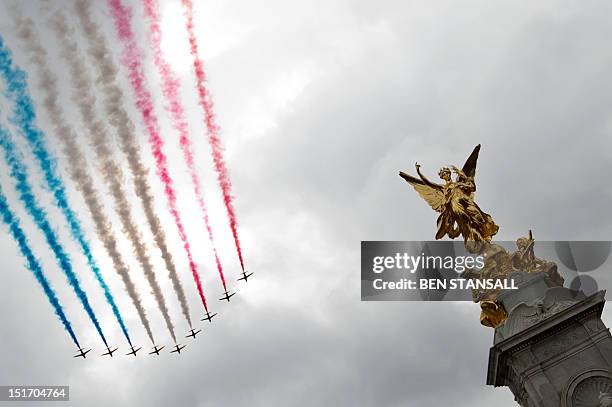 The British Royal Air Force Red Arrows aerobatic display team fly past the Queen Victoria Memorial in front of Buckingham Palace after a parade...