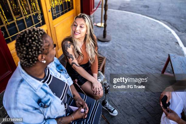 friends talking outdoors - adult sitting bench sidewalk stock pictures, royalty-free photos & images