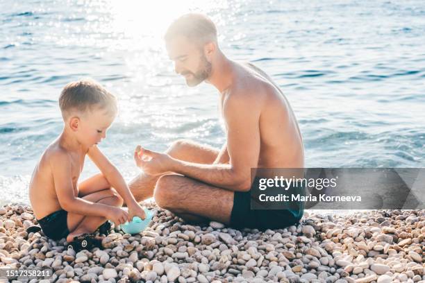 father and son enjoying sea. - extreem weer stock pictures, royalty-free photos & images