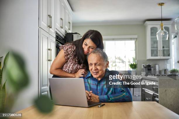 daughter assisting father on how to use the computer - healthcare professional stock pictures, royalty-free photos & images