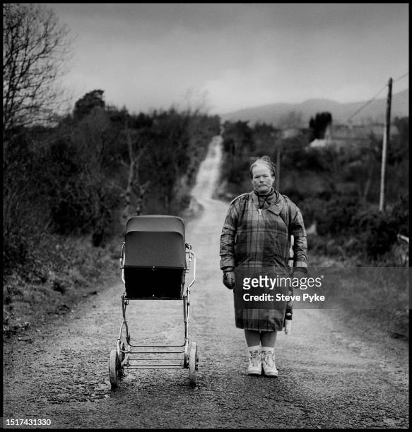 Woman standing with a pram filled with potatoes on a road in County Kerry in Ireland, 1994. Photograph from I Could Read the Sky, a now-classic novel...
