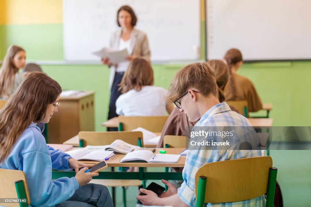 Teenagers using phones during lesson