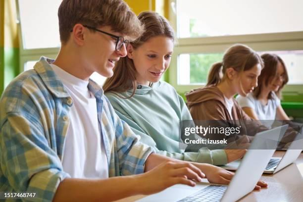 adolescentes usando computadoras portátiles en el aula - edificio de escuela secundaria fotografías e imágenes de stock