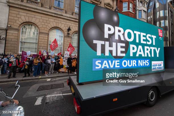 Mobile digital sign drives past as UNITE members and Save Our NHS activists protest outside a Conservative party fundraiser at the Carlton Club on...