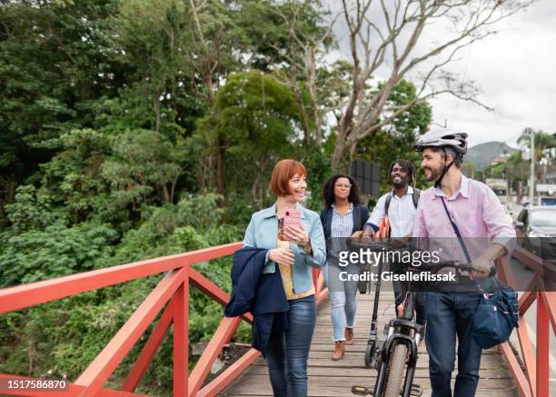 multiracial group of people walking across a bridge during their commute - farewell colleague stock pictures, royalty-free photos & images
