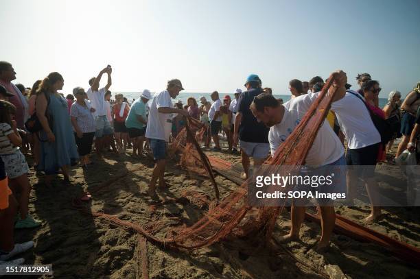 Locals are seen removing nets to capture fish after taking part in the 'La Tirada del Copo' exhibition at Los Boliches beach. Every year in...