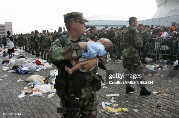 Soldier tends to a baby as people wait to leave the Superdome in New Orleans 01 September 2005. Rampant lawlessness prompted Louisiana state leaders...