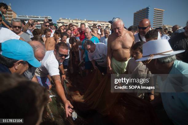 Locals throw fish into the water as they take part in the 'La Tirada del Copo' exhibition at Los Boliches beach. Every year in Fuengirola, locals...