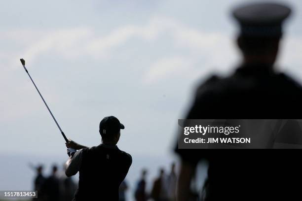 Tiger Woods of the US is watched by a police officer as he shoots from the 15th fairway during the third round of the 133rd Open Championship 17...