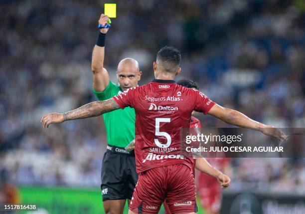 Referee Michel Morales gives a yellow card to Anderson Santamaria of Atlas during the Mexican Apertura 2023 tournament football match between...