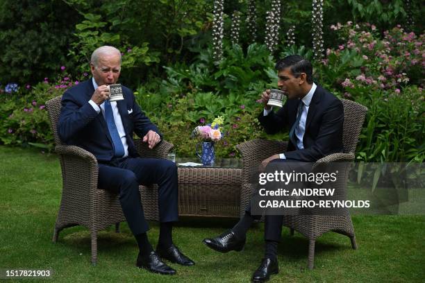 Britain's Prime Minister Rishi Sunak and US President Joe Biden drink ffrom mugs as they sit in the garden of 10 Downing Street in central London on...