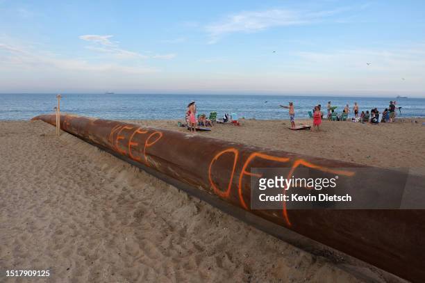 Pipe from a sand pumping barge off-shore lays across the beach as the Army Corps of Engineers continues their beach and dune replenishment project on...